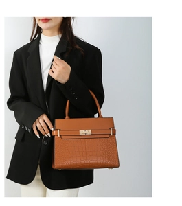 Detail of brown leather handbag with crocodile pattern texture and metal rotary clasp