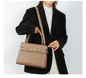 Detail of crocodile embossed leather tote with gold twist lock and handle for women