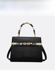 Detailed view of black crocodile pattern leather tote with snake skin handles and gold clasp