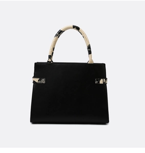 Detail of classic black leather handbag featuring stylish snakeskin print handles