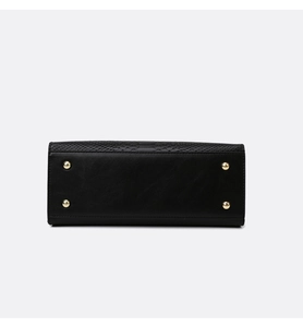 Detailed base of black handbag with four protective gold metal studs and embossed texture