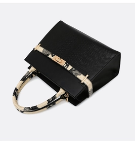 Close-up of black leather handbag featuring snakeskin texture handle and gold clasp lock