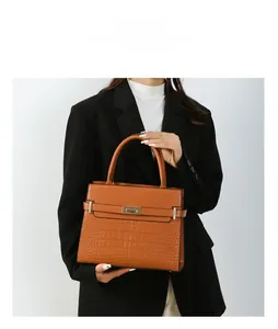 Detailed view of brown crocodile pattern handbag featuring a gold twist lock and handle