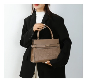 Detail of mocha brown tote featuring crocodile embossed leather and metal twist lock