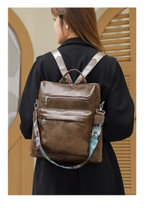 Detail of vintage brown backpack featuring geometric stitching and colorful ethnic strap