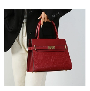Macro detail of red faux leather handbag with crocodile pattern and golden metal lock