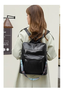 Detail of black faux leather backpack with a colorful floral woven shoulder strap