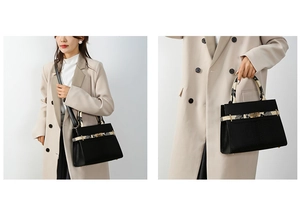 Detail of black leather handbag with snakeskin pattern handles and gold twist lock