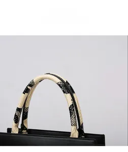 Detail display of the black tote bag featuring a snakeskin pattern round top handle