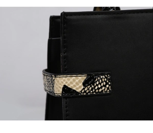 Detail of matte black handbag featuring snakeskin texture trim and precise stitching