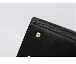 Macro view of black leather bag base with golden metal feet and embossed texture