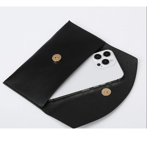 Detail view of the black leather clutch bag with a golden magnetic clasp and phone compartment