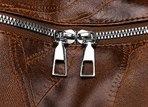 Detail of dual metal zippers and textured leather on a vintage brown travel backpack