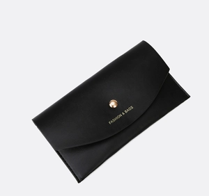 Detail of black leather handbag featuring a gold metal clasp and fashion logo print