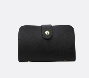Detail shot of black pebbled leather texture and gold cylindrical clasp on stylish handbag