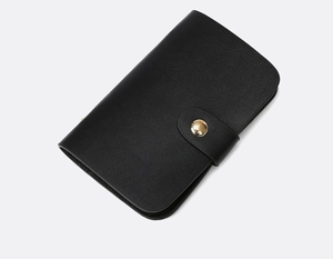 Detail of minimalist black leather wallet with a polished gold round button closure