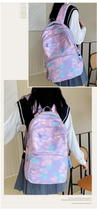 Detail of purple star-print nylon backpack featuring multiple pockets and astronaut charm