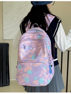 Detail of light purple nylon backpack featuring white star patterns and astronaut pendant