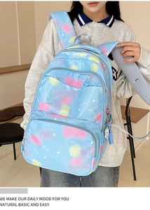 Detail of blue nylon backpack featuring starry nebula print and astronaut charm pendant