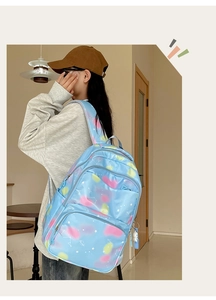 Detail of light blue nylon backpack with cloud patterns and astronaut charm on a model