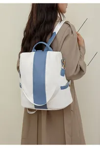 Detail of color-block backpack with anti-theft design and blue vertical stripes on model