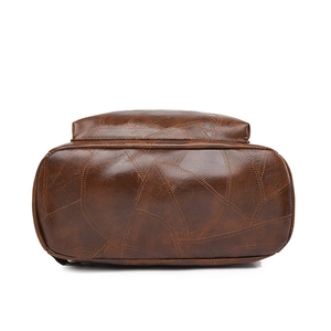 Bottom view of a vintage brown leather backpack showing faux leather texture and stitching