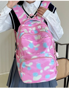 Pink nylon backpack detail showing multiple zippers, cloud patterns and white plush pendant