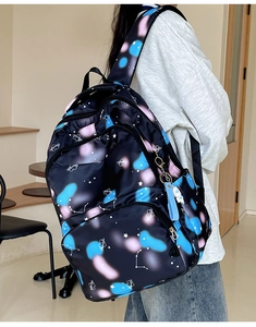 Macro detail of nylon backpack with nebula print and astronaut charm on side pocket