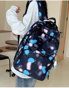 Detail of black nylon backpack featuring constellation prints and astronaut charm accessory