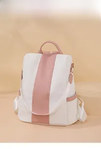 Detail of white and pink faux leather backpack with fabric straps on a soft peach pedestal