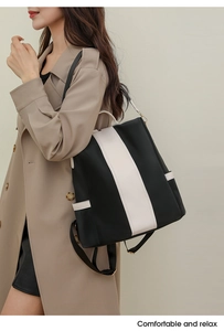 Woman wearing a large black and white striped anti-theft backpack over a khaki coat