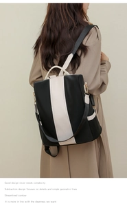 Detail of a black and white contrast backpack with side pockets on a model in a trench coat