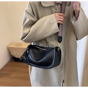 Detail of black saddle bag with textured leather and a wide geometric pattern strap