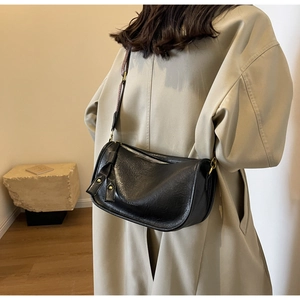 Detail of black leather saddle bag with knotted shoulder strap and gold hardware accents