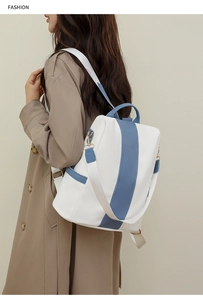 Blue and white color-block leather backpack on model wearing khaki trench coat