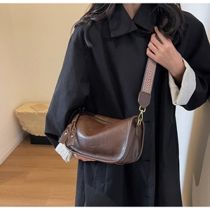 Detail of vintage brown saddle bag showing leather texture and woven shoulder strap