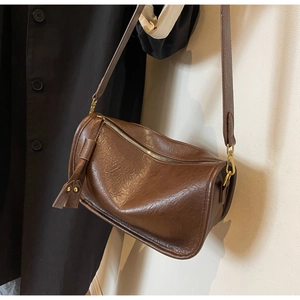 Brown faux leather saddle bag with tassel detail worn as a vintage crossbody style
