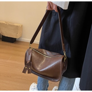 Close-up of brown leather Boston bag with metal buckles and adjustable shoulder strap