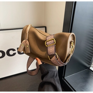 Detail of brown cylinder saddle bag with adjustable geometric patterned strap