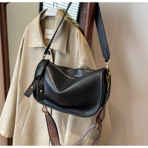 Detail of black faux leather saddle bag with interchangeable woven and leather straps