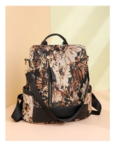 Detail of bohemian floral tapestry pattern and black leather trim on nylon backpack