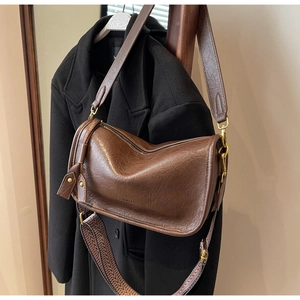 Close-up of soft faux leather cylindrical bag with wide strap and woven ethnic strap