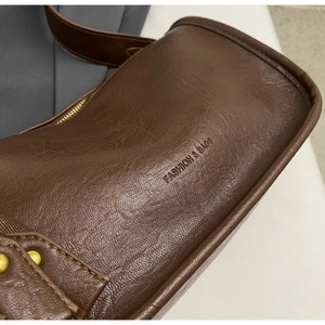 Macro view of brown leather texture and gold zipper detail on vintage saddle bag