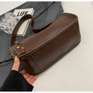 Detail of dark brown leather saddle bag with gold hardware and embossed fashion text