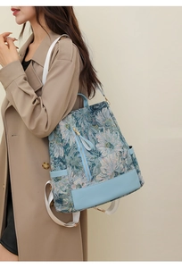 Detail of floral nylon backpack with leather trim and white webbing shoulder strap