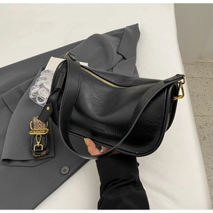 Detail of vintage textured black saddle bag with golden zippers and patterned strap