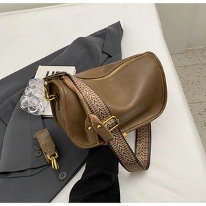 Detail of soft leather saddle bag with wide jacquard shoulder strap and gold hardware