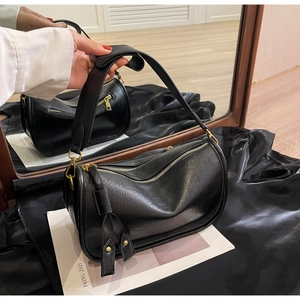 Close-up of black lychee grain leather saddle bag with gold metal zippers and hardware