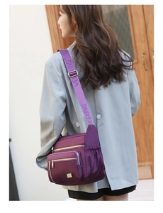 Detail view of purple oxford fabric shoulder bag with gold zippers and jacquard strap