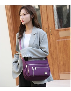 Close-up of purple oxford fabric shoulder bag with multiple zippers and wide strap detail